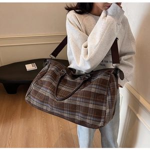 Détail d'un sac de voyage à carreaux vintage avec poignées en cuir et bandoulière réglable