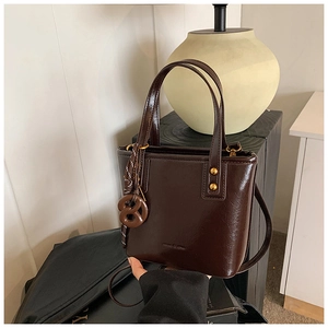 Détail du sac seau en cuir ciré marron foncé avec foulard en soie et breloque biscuit