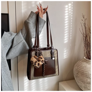 Detail of contrast stitching tote bag with leopard heart charm and leather finish