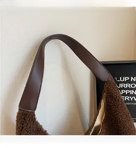 Detail eines robusten braunen Ledergriffs an einer weichen braunen Plüschtasche