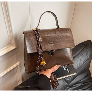 Détail d'un sac à main vintage en cuir marron avec boucle métallique et pendentif cloche