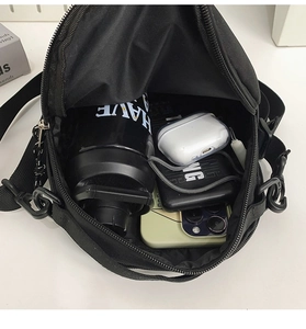 Détail de l'intérieur spacieux du sac à bandoulière noir en nylon pour les objets du quotidien