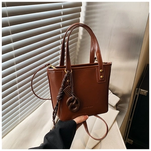 Détail du sac seau en cuir marron vintage avec nœud tressé et finitions en rivets métal