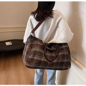 Gros plan sur un sac de voyage à carreaux avec poignées en cuir marron et bandoulière