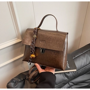 Détail d'un sac à main en cuir marron vintage avec corde tressée et clochette dorée