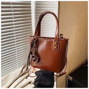 Détail du sac cabas en cuir ciré caramel avec bandoulière et pendentif décoratif