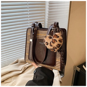 Close-up of contrast tote bag featuring houndstooth pattern and leopard heart charm