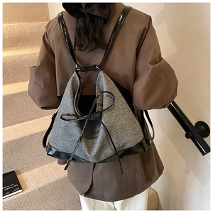 Detail of grey tweed backpack with black leather bow and straps worn by model