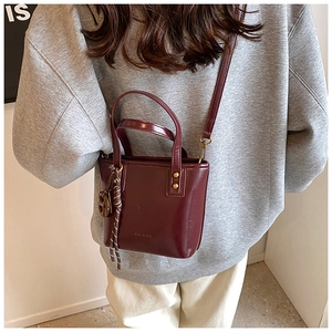 Détail d'un mini sac cabas bordeaux en cuir ciré avec charm de poignée tressé