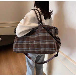 Détail d'un grand sac de voyage à carreaux avec poignées en cuir et bandoulière large