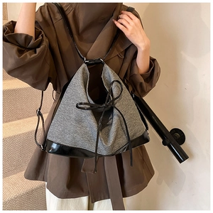 Detail of tweed tote backpack with leather trim and decorative bow on stairs