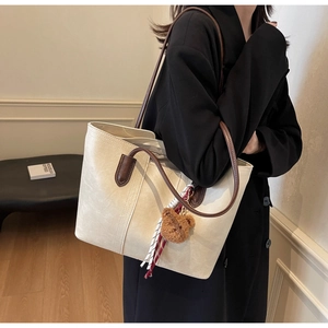 Detail view of large cream tote bag with brown straps and cute bear charm pendant