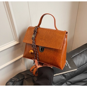 Vue détaillée du sac à main vintage marron avec fermoir métallique et breloque cloche