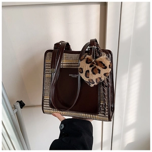 Detail of contrast color tote bag with plaid pattern and leopard heart charm