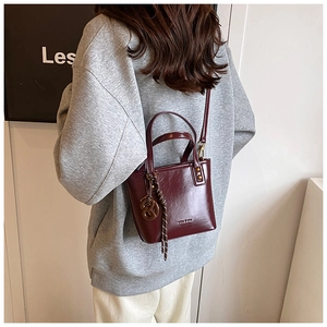 Détail d'un sac seau rouge foncé avec poignées élégantes et bandoulière amovible