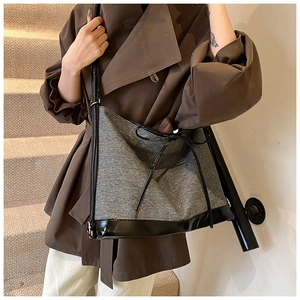 Detailed view of grey tweed tote bag with black patent leather bow and shoulder straps