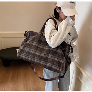 Détail du sac de voyage à carreaux bleus et marrons avec des poignées en cuir durable