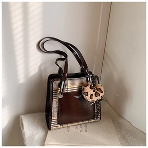 Detail view of contrast stitching and leopard heart charm on a vintage houndstooth tote bag