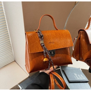 Détail du sac vintage en similicuir marron avec lanière tressée et pendentif doré