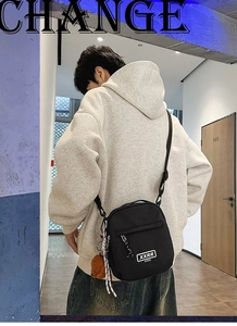 Vue arrière d'un sac bandoulière noir avec charm ours sur un sweat à capuche gris