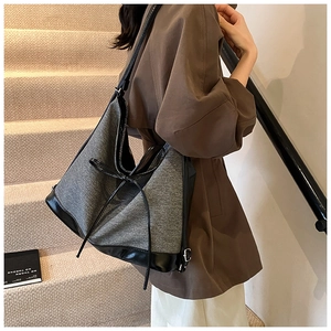 Detail of grey wool and black leather patchwork tote bag with bow tie accent
