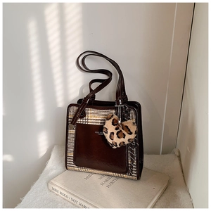Detail of color-block tote bag in brown leather and plaid fabric with leopard heart charm