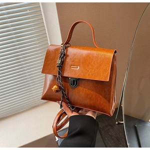 Détail d'un sac à main vintage marron avec charm de cloche dorée et boucle métallique