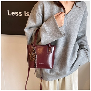 Détail du sac seau bordeaux brillant avec breloques chic et fine bandoulière amovible