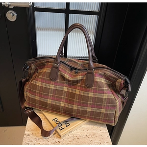 Détail du sac de voyage à carreaux rétro avec poignées en cuir et bandoulière réglable