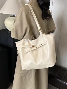 Minimalist beige oversized tote bag with decorative leather straps for commute and travel