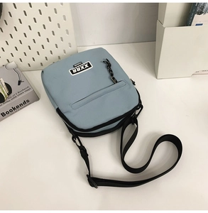 Détail d'un sac bandoulière en toile bleu clair avec sangle réglable et écusson