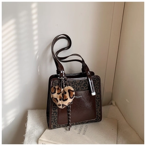 Close-up of contrast tote bag with leopard print heart charm and branded text detail