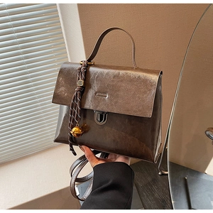Détail d'un sac à main rétro en cuir marron avec fermoir métallique et breloque tressée