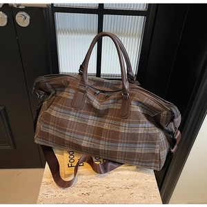 Vue détaillée du grand sac de voyage à carreaux café avec sangles en cuir et ferrures en métal