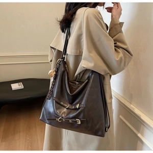 Side view of a large dark brown PU leather tote bag worn with a khaki trench coat