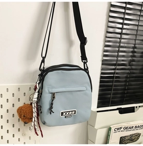 Détail du sac bandoulière en nylon bleu clair avec poche zippée et pendentif chien en peluche