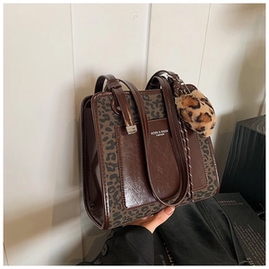 Close-up of contrast tote bag with leopard print side panels and heart plush pendant