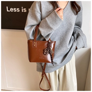 Détail du sac seau en cuir marron avec bandoulière et pendentif en forme d'anneau