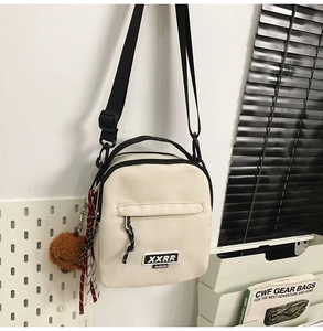 Détail de la sacoche crème avec pendentif chien en peluche et bandoulière réglable
