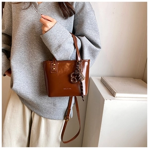 Détail d'un sac seau en cuir marron avec logo vintage et breloque décorative en foulard de soie
