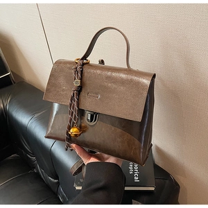 Détail d'un sac à main en cuir marron avec cordon tressé et pendentif cloche dorée