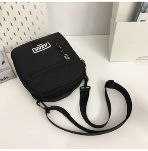 Gros plan d'un sac bandoulière noir en nylon avec logo blanc sur un bureau blanc