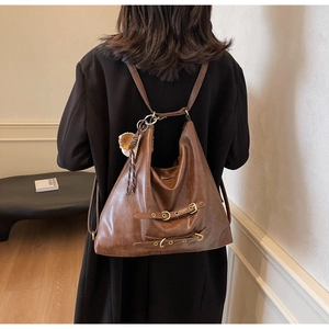 Detail view of brown faux leather backpack with metallic buckle straps and soft texture