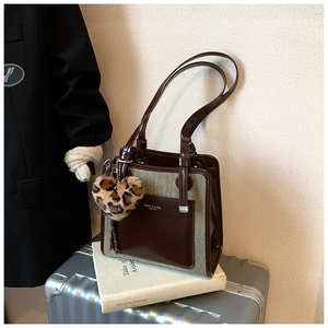 Detail of contrast tote bag with leopard heart charm on a silver suitcase