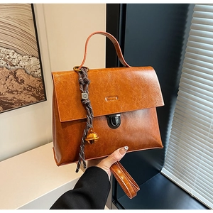 Détail d'un sac à main en cuir marron vintage avec boucle en métal et breloque cloche