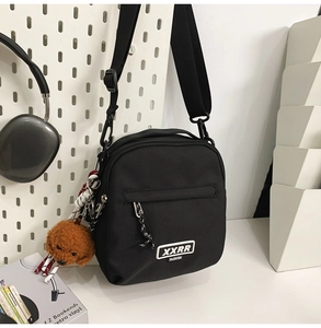 Détail du sac bandoulière noir en nylon avec charm d'ours en peluche et sangle réglable