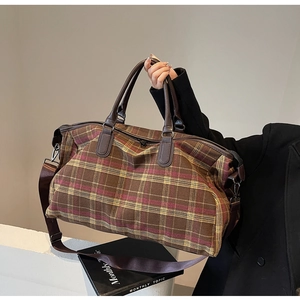 Gros plan du sac de voyage à carreaux avec poignées en cuir et bandoulière réglable
