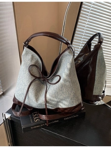 Blue denim and brown leather tote bag with bow detail shown in mirror reflection