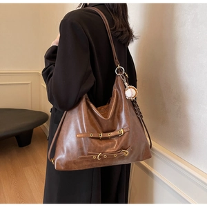 Close-up of brown large capacity hobo bag with leather straps and baseball pendant