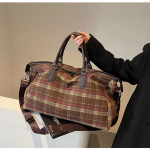 Détail du sac de voyage à carreaux avec poignées en cuir et bandoulière réglable